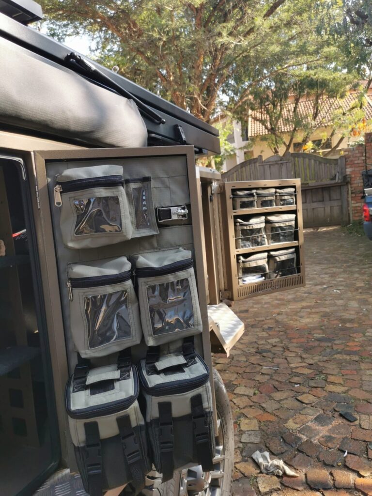 Custom Canvas caddie with two removable shower bags and three fixed zipped bags with clear PVC windows and an open pocket to the tent side rear door and fixed zipped bags with windows to the front door on the tentside of a Metalian Maxi 40.