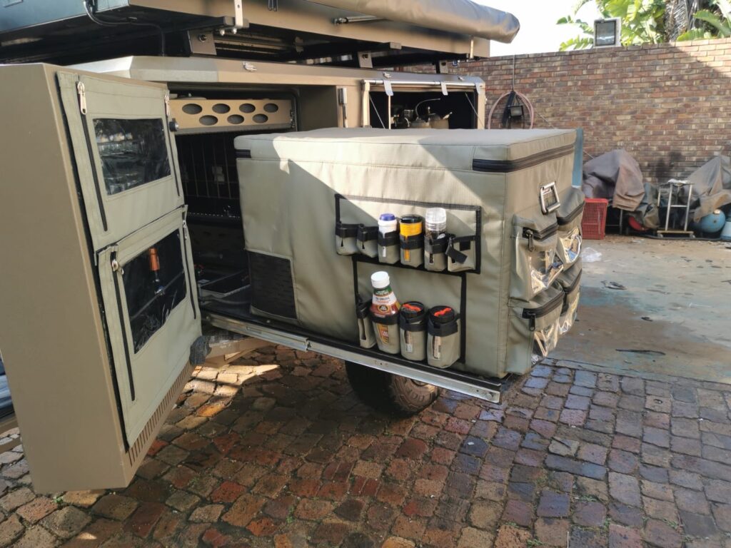 Custom Shelf flaps and Fridge cover to hold spices and condiments, plastic bags and other random items fitted to a Metalian Maxi camping trailer.