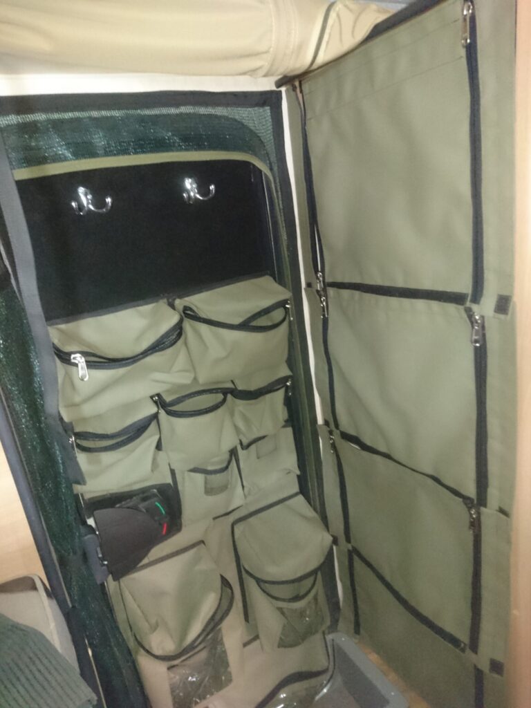 Custom Canvas Caddie with fixed zipped bags and removable shower bags in the door of a Jurgens Xplorer.