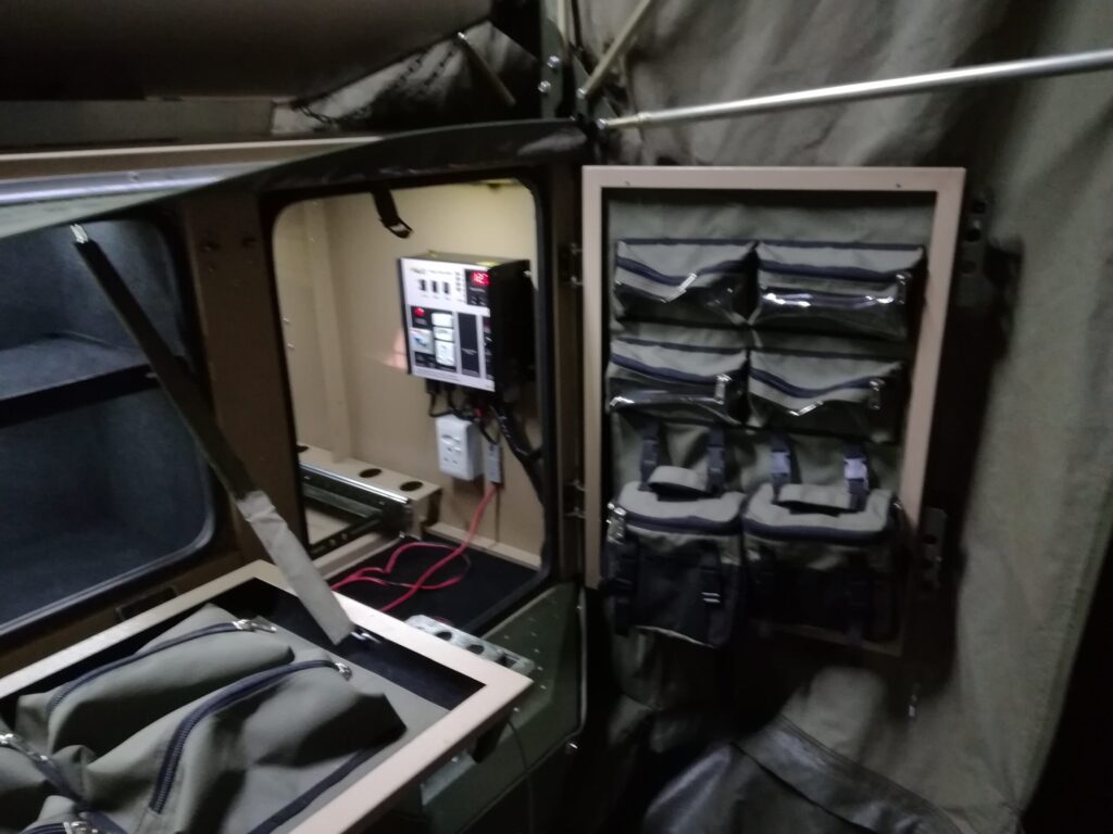 Custom Canvas Zipped bags with clear PVC windows and removable shower bags in the flip-down tentside door of a Conqueror Courage Trailer.