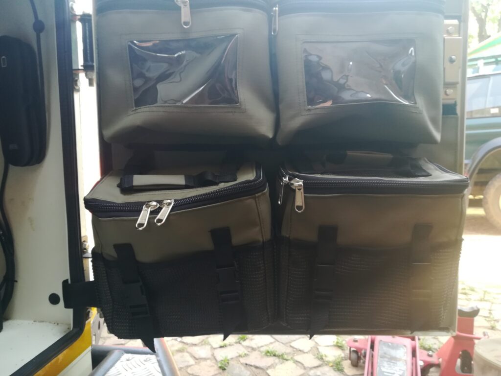 Custom Canvas caddie with zipped bags with PVC windows and removable shower bags installed into the front tent side door of a Jurgens XT camping trailer.